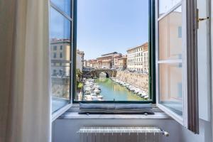 a window with a view of a river and a bridge at Livorno-Mercato delle Vettovaglie Central Apt! in Livorno