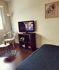 a room with a television on a stand with a chair at Cozy Studio Strasbourg in Strasbourg +9 photos