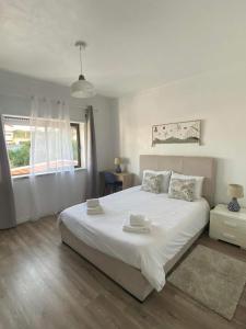 - une chambre blanche avec un grand lit et une fenêtre dans l'établissement Casa do coral, à Peniche