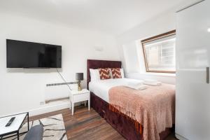 a white bedroom with a bed and a flat screen tv at Piccadilly Circus by Capital in London