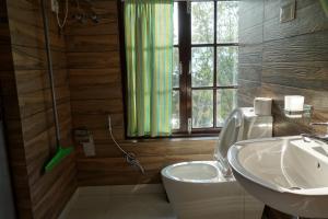La salle de bains est pourvue d'un lavabo, de toilettes et d'une fenêtre. dans l'établissement Mintokling Guest House, à Gangtok