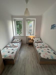 dwa łóżka w pokoju z dwoma oknami w obiekcie Manufaktura Rooms w Łodzi