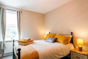 a bedroom with a bed with yellow pillows and a window at Steeple View House in Lincolnshire