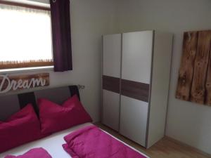 um quarto com um armário branco e almofadas cor-de-rosa em FEWO CELINE em Wasserhofen