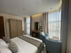 a hotel room with a bed and a chair and window at شقق عالية الاطلالة Serv Apartment in Hafr Al-Batin