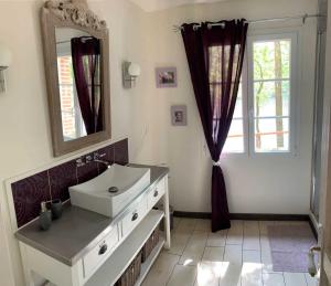 een badkamer met een wastafel, een spiegel en een raam bij La maison au bord du lac in Château-Guibert
