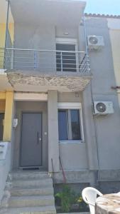 een wit huis met een trap, een deur en een balkon bij Sea La Vie in Korinthos