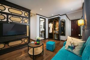 a living room with a blue couch and a tv at Media Central Hotel & Spa in Hanoi