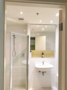 a bathroom with a shower and a sink and a mirror at SUNSET GETAWAY GLENELG in Glenelg