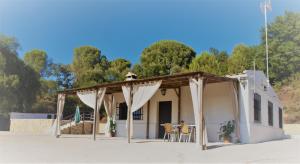 a small white building with awning and tables at CASA RURAL TRIGUEROS in Córdoba