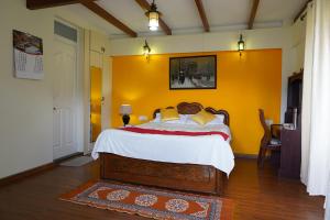 a bedroom with a bed and a yellow wall at Church Hill Cottage in Ooty