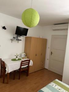 una sala da pranzo con tavolo e lampada verde di Longa Rooms a Šibenik