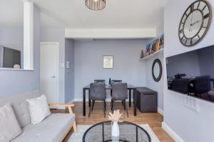 a living room with a couch and a table with chairs at Aryas Apartments London in London