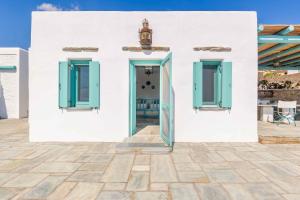 a white house with blue doors and a patio at Magganari View Village in Manganari