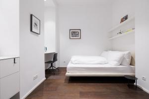 a white bedroom with a bed and a desk at Design Apartment Spittelberg - 7th district - contactless checkin in Vienna