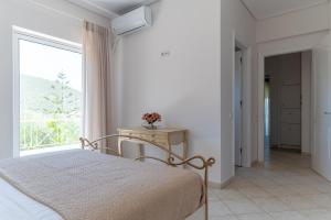 a white bedroom with a bed and a window at Villa Katrin 2 in Pylos