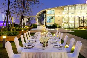 a long dining table with white chairs and candles at Langham Place Guangzhou - Walking distance to Canton Fair in Guangzhou