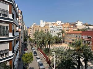 una calle de la ciudad con coches, palmeras y edificios en Piso Centro Elche junto Basílica, en Elche