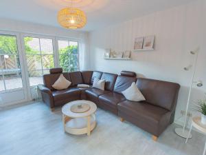 un salon avec un canapé en cuir marron et une table dans l'établissement Ferienhaus Lüttjes Strandhus, FeWo Vermittlung Nordsee, à Dangast 12 autres photos