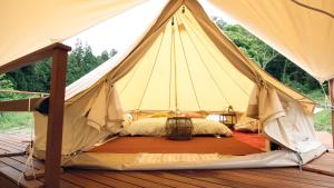 a bed in a teepee tent on a deck at ties Camp Ground Nagiso in Nagiso