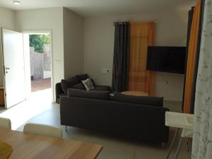 sala de estar con sofá negro y TV en וילה בגליל Vila Galilee, en Shadmot Devora