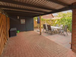 un patio avec une table et des chaises blanches et une table et une table dans l'établissement Ferienhaus Lüttjes Strandhus, FeWo Vermittlung Nordsee, à Dangast