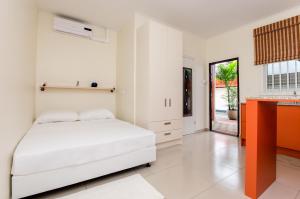 a white bedroom with a bed and a desk at Elementz Apartments in Paramaribo +61 photos