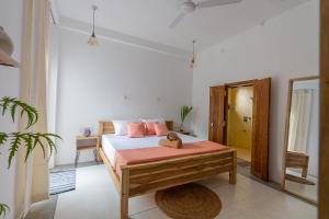 a bedroom with a bed with pink pillows and a mirror at NETS Cowork & Colive in Ahangama