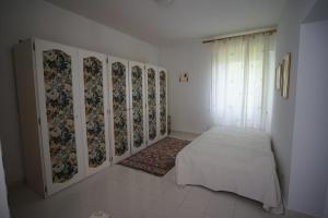 una camera bianca con un letto e una finestra di Villa Helma Lago Maggiore a Caravate
