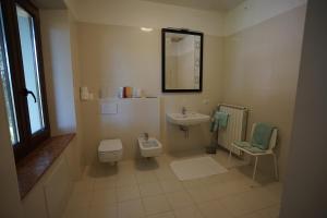 bagno con servizi igienici, lavandino e specchio di Villa Helma Lago Maggiore a Caravate