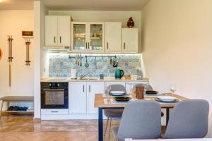 a kitchen with white cabinets and a table and chairs at Villa Kometa Pamporovo Cozy 1-BD Flat by Flat Mаnager in Pamporovo