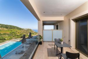 a balcony with a pool and a table and chairs at Sky View Suites Kefalonia in Vóvikes