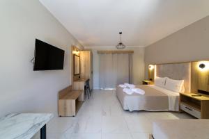a hotel room with a bed and a flat screen tv at Sky View Suites Kefalonia in Vóvikes