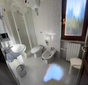 La salle de bains blanche est pourvue d'un lavabo et de toilettes. dans l'établissement B & B La Pineta By La Capannina, à Roccaraso