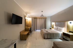 a hotel room with two beds and a flat screen tv at Sky View Suites Kefalonia in Vóvikes
