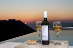 a bottle of wine and two wine glasses on a table at Sky View Suites Kefalonia in Vóvikes