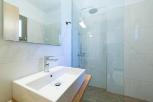 a white bathroom with a sink and a shower at Sky View Suites Kefalonia in Vóvikes