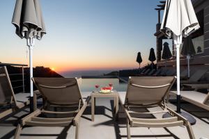 two chairs and a table on a balcony with the sunset at Sky View Suites Kefalonia in Vóvikes