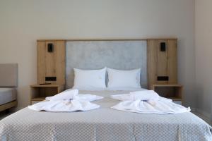 a bed with white sheets and towels on it at Sky View Suites Kefalonia in Vóvikes