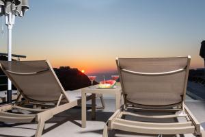 two chairs and a table on a balcony with a sunset at Sky View Suites Kefalonia in Vóvikes