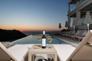 a bottle of wine and two glasses on a table at Sky View Suites Kefalonia in Vóvikes