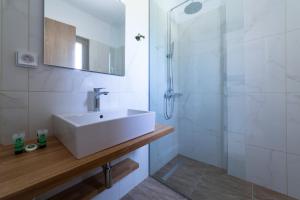 a white bathroom with a sink and a shower at Sky View Suites Kefalonia in Vóvikes