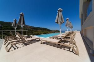 a row of lounge chairs and umbrellas on a building at Sky View Suites Kefalonia in Vóvikes