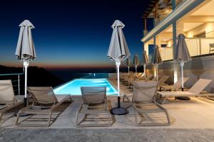 a group of chairs and umbrellas next to a swimming pool at Sky View Suites Kefalonia in Vóvikes