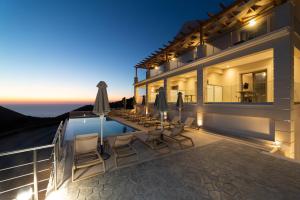 a villa with a swimming pool at night at Sky View Suites Kefalonia in Vovikes