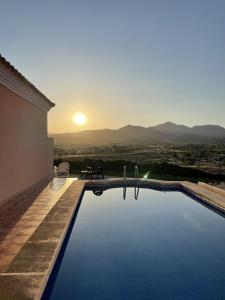 una piscina con il tramonto sullo sfondo di Villa Buena Vista a San Vicente del Raspeig