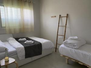 Un dormitorio con 2 camas y una escalera. en וילה בגליל Vila Galilee, en Shadmot Devora