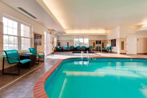 a pool in a hotel lobby with chairs and tables at Residence Inn Indianapolis Fishers in Fishers