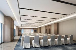 una sala de conferencias con una mesa larga y sillas blancas en Fairfield by Marriott Zibo en Zibo