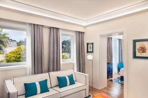 a living room with a white couch and two windows at Pazziella Garden & Suites in Capri